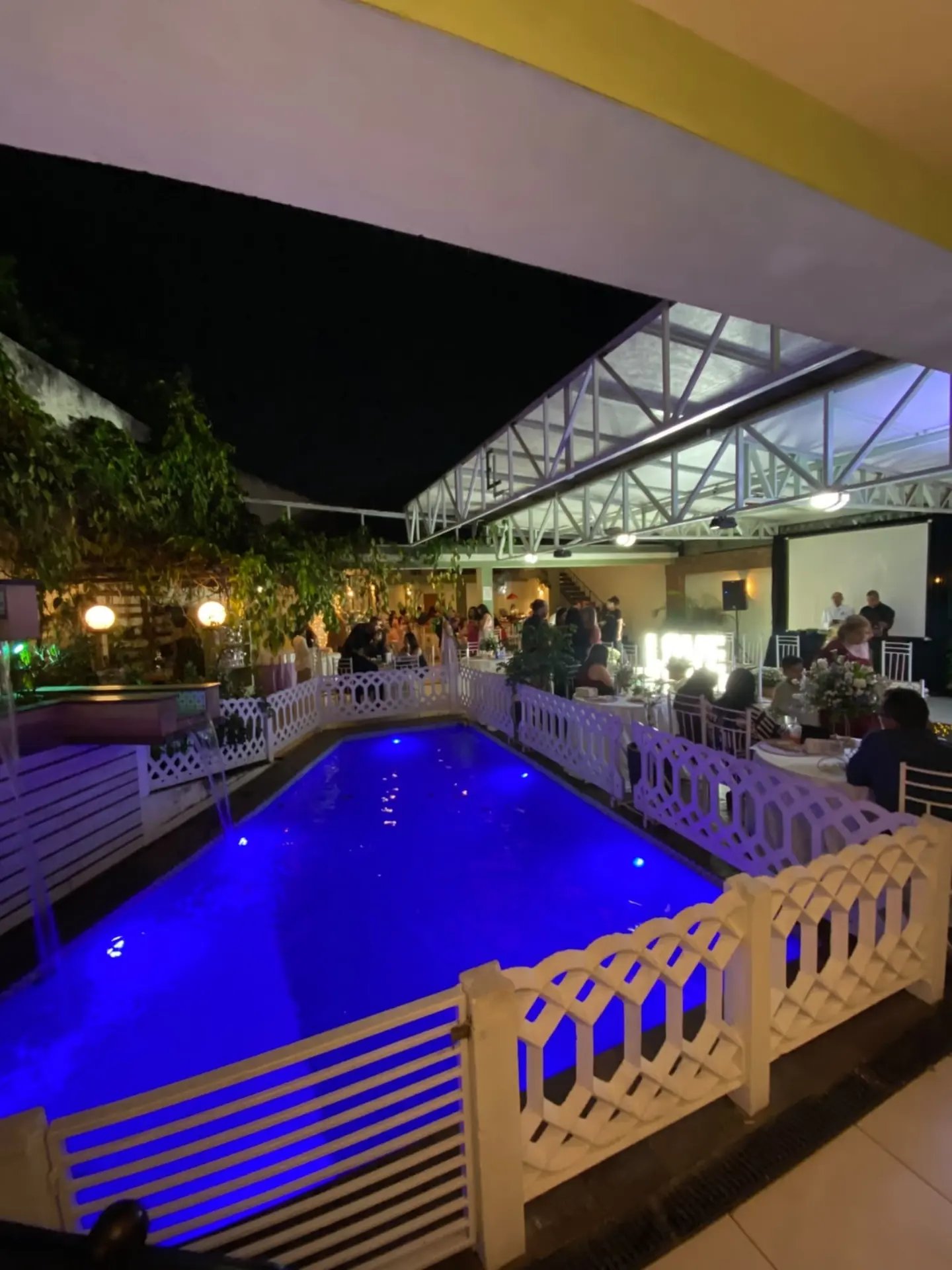 Piscina iluminada ao lado do salão principal durante um evento